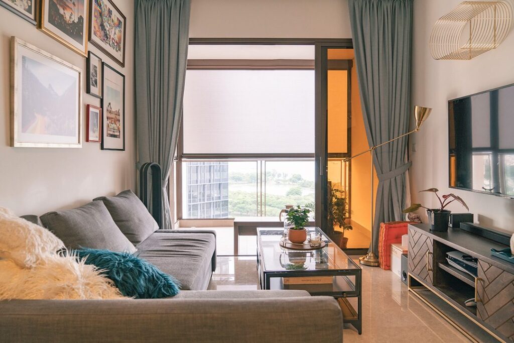 Ziptrak screen with side curtains in a cosy Singapore living room overlooking a balcony and city view.