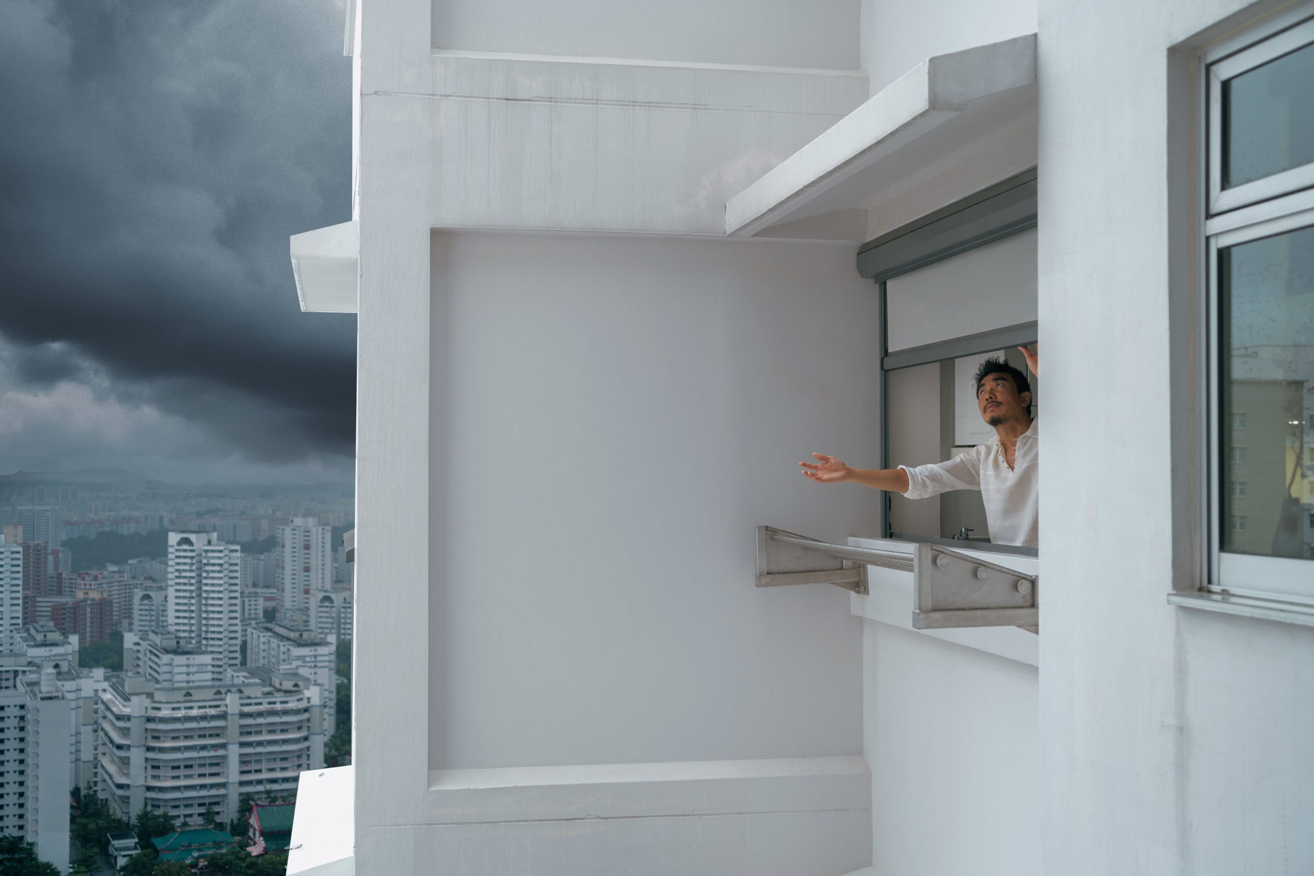 Weather-proof Ziptrak zip blinds installed in a high-rise HDB service yard to prevent rain splashing and protect laundry area.