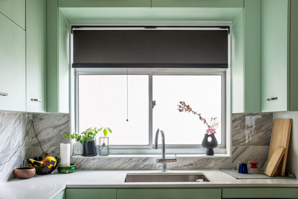 Dark grey PVC roller blinds over a kitchen sink paired with mint green walls