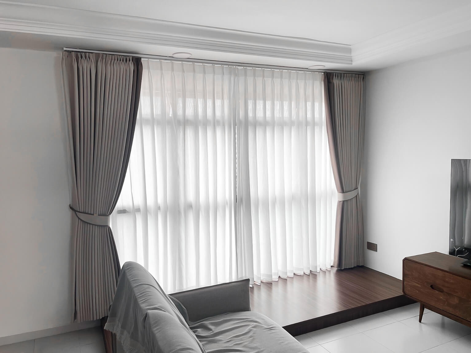 Sheer day and grey night curtains on a raised platform in a living room