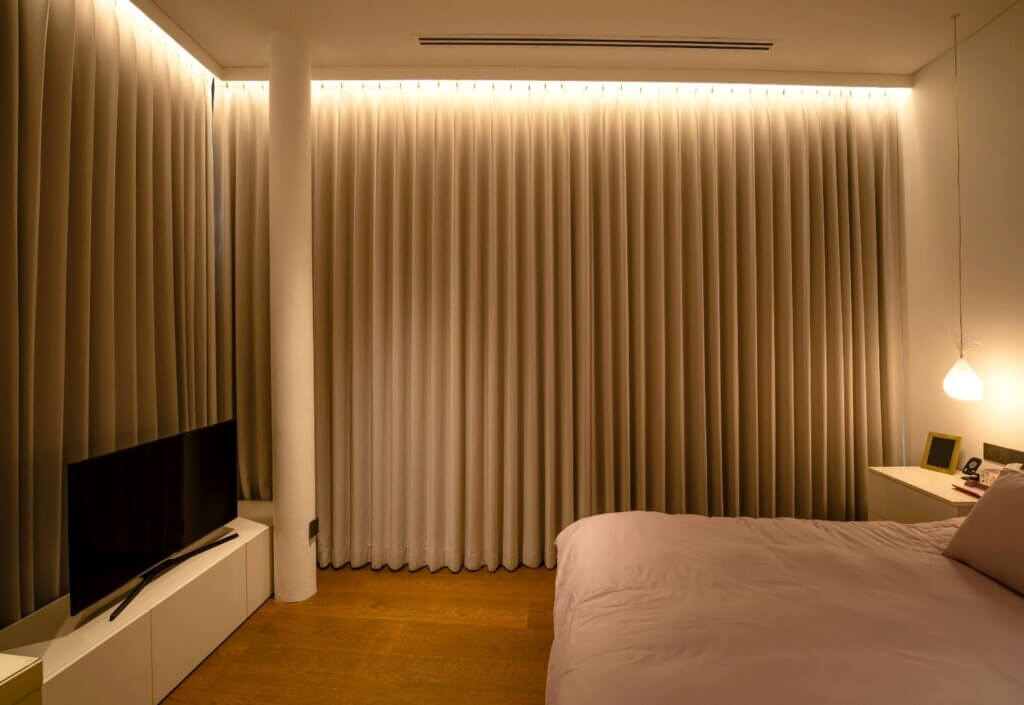Warm and elegant bedroom with full-length blackout curtains, soft lighting and a calm modern interior in Singapore