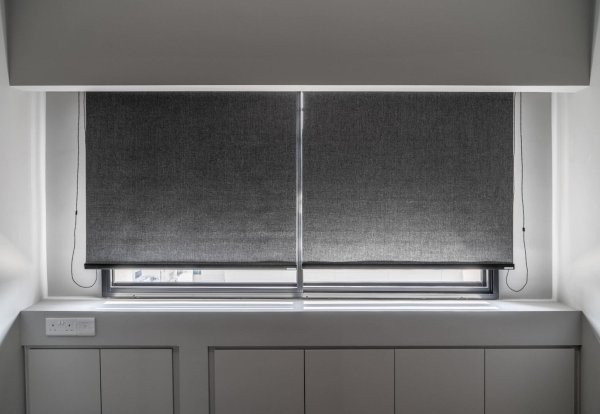 blackout-roller-blinds-singapore-no-u-channels Blackout roller blinds installed in a Singapore bedroom without U-channels, showing light gaps at the sides and bottom