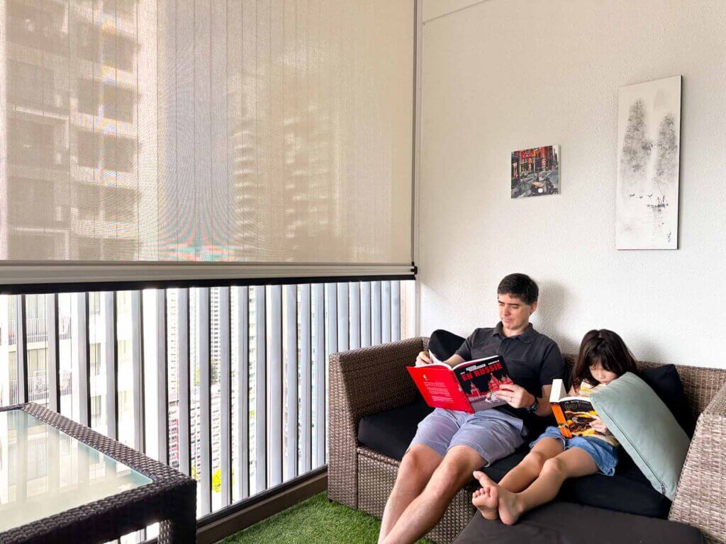 Ziptrak and Invisible Grilles in a condo balcony in Singapore with father and son reading